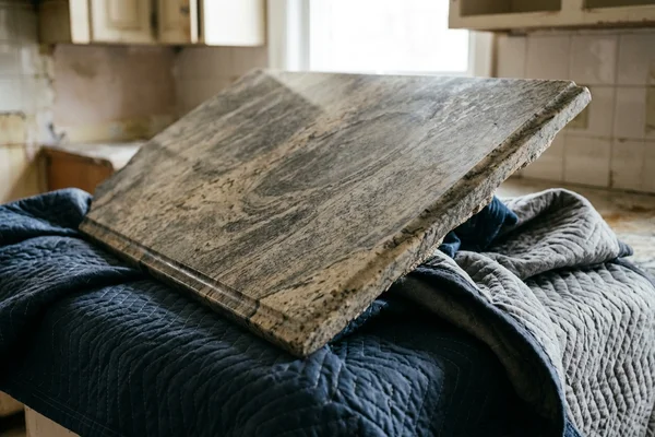 Old granite countertop being removed on protective blankets